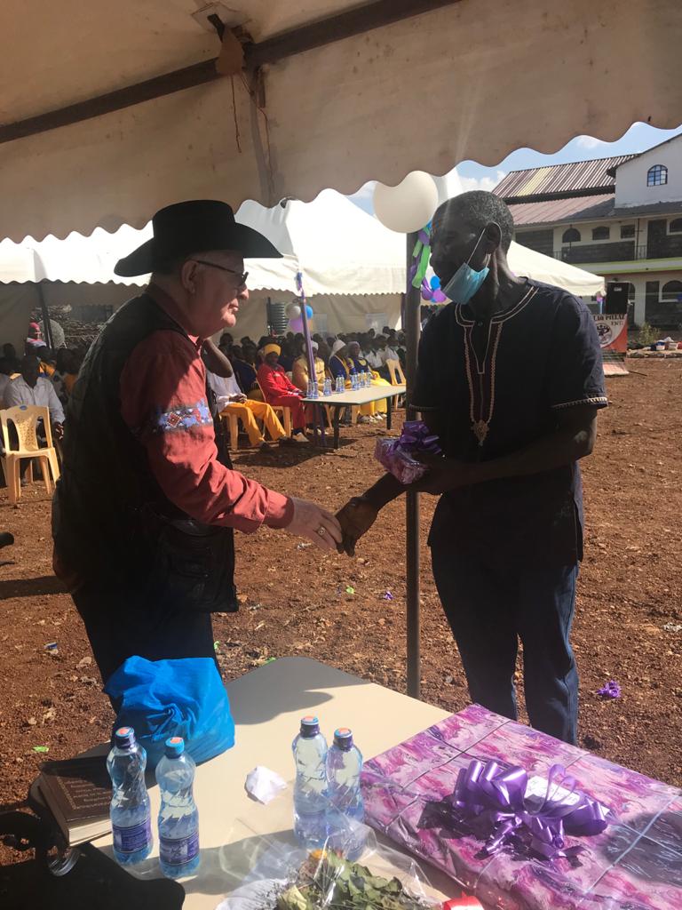 George hands a gift to a Juanita School staff member, Machaga
